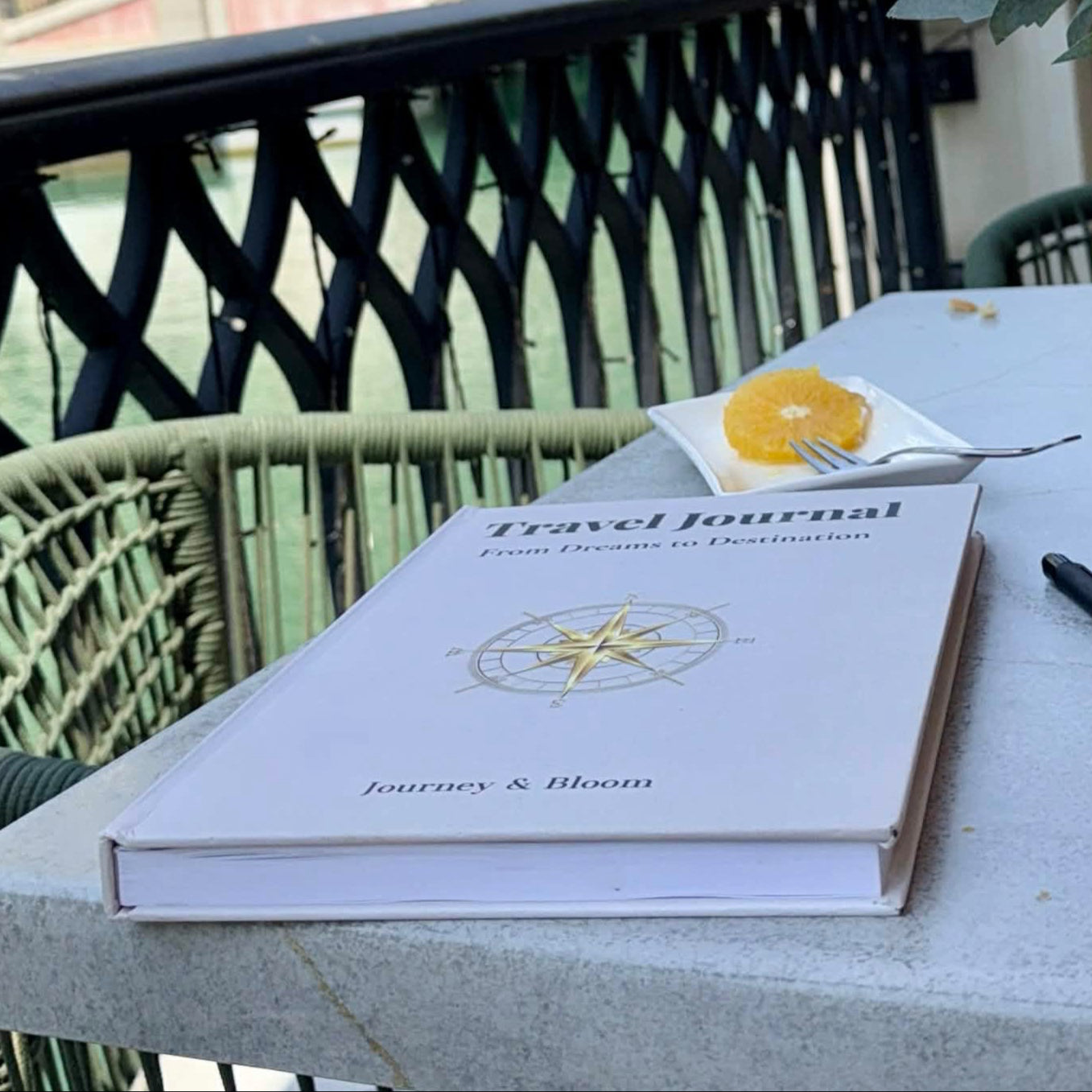 Travel Journal on coffee table with a pen and flower.